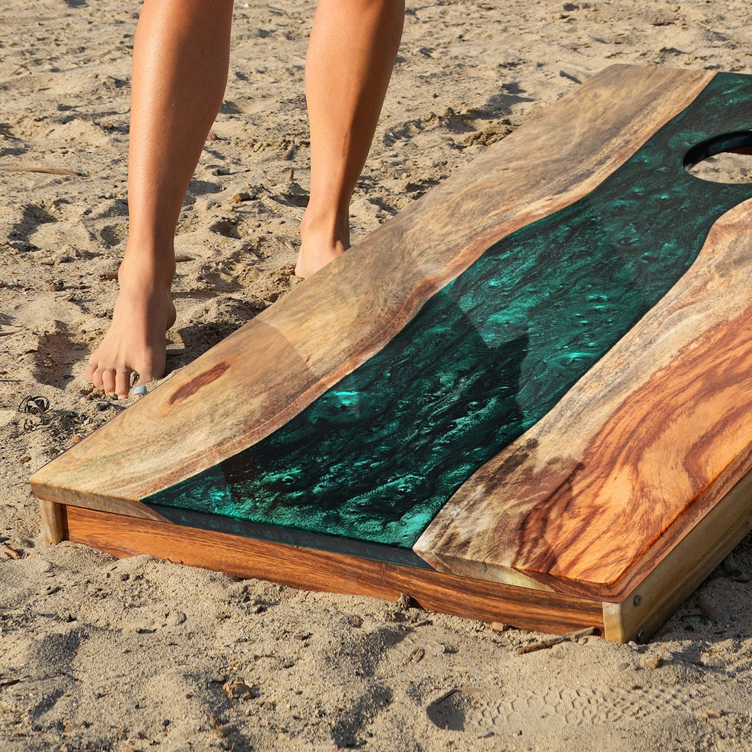 Wooden board with green resin on a sandy surface