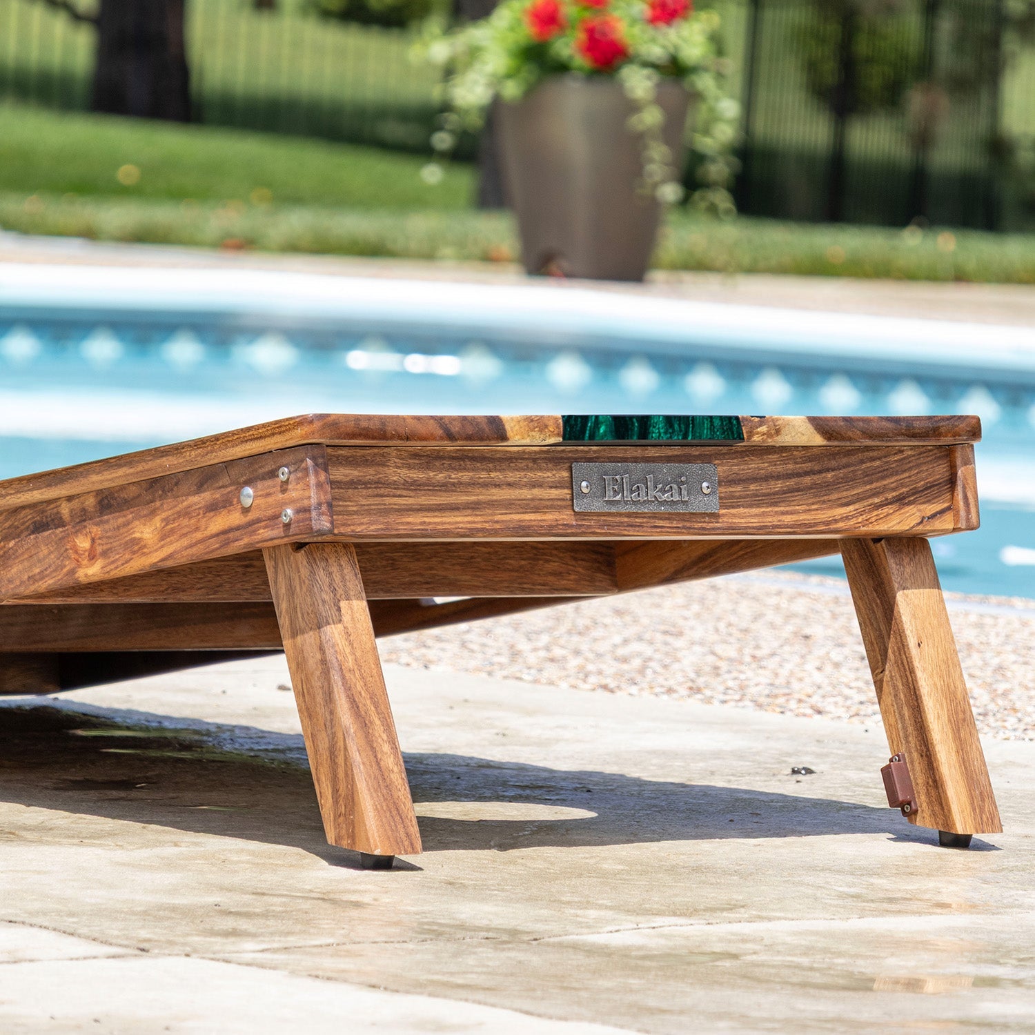 Wooden pool float with 'Elakat' branding by a poolside