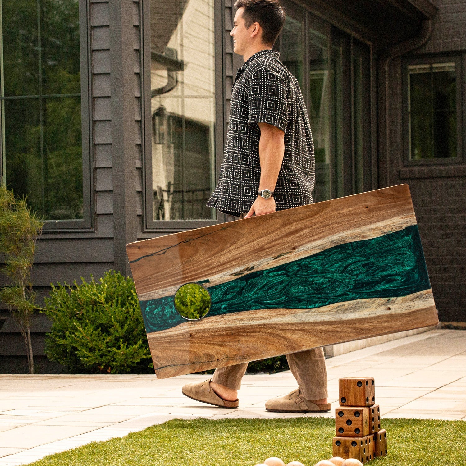 Person holding a large wooden board with a house in the background