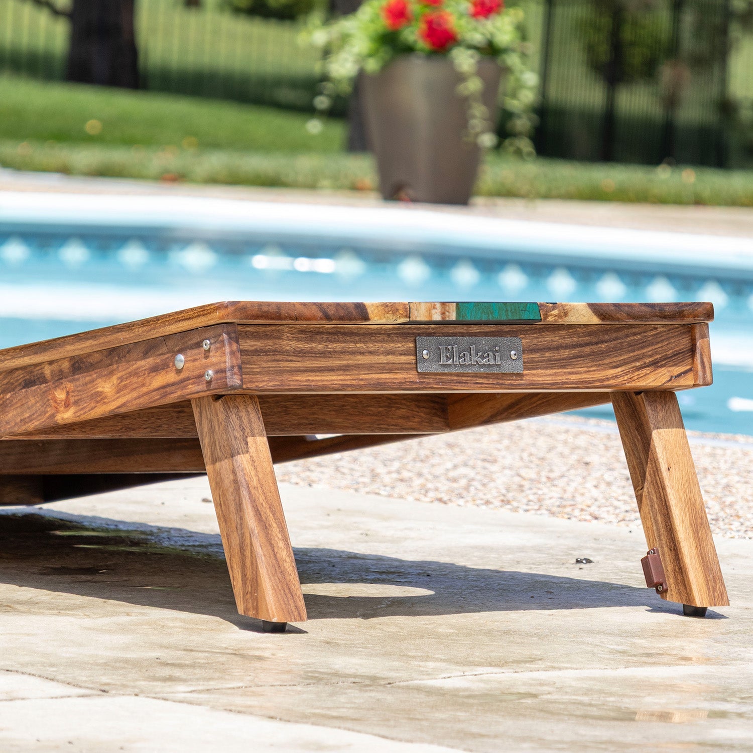 Wooden pool float with 'Elakat' branding by a poolside