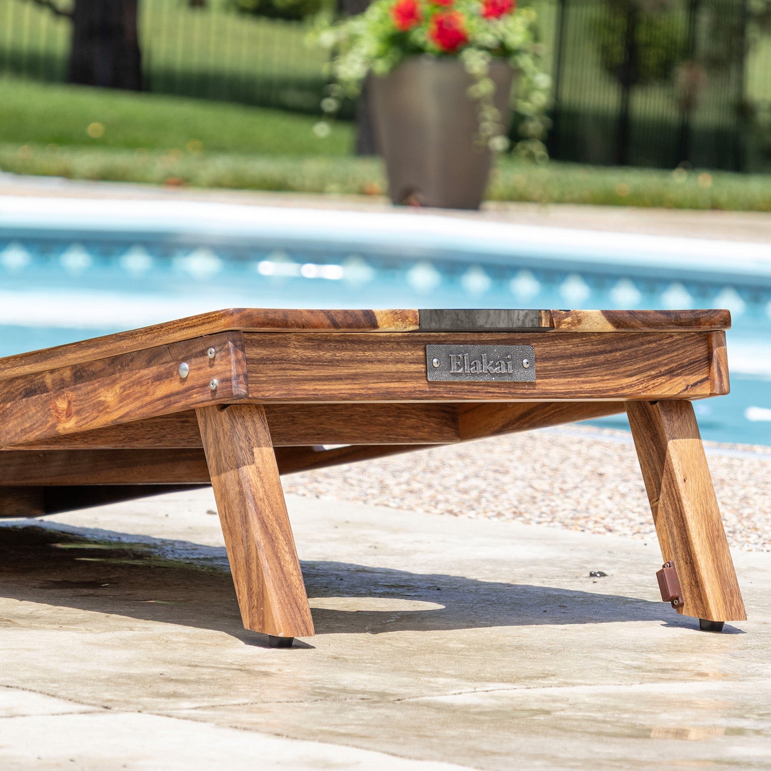 Wooden lounge chair with 'Elakat' branding by a poolside