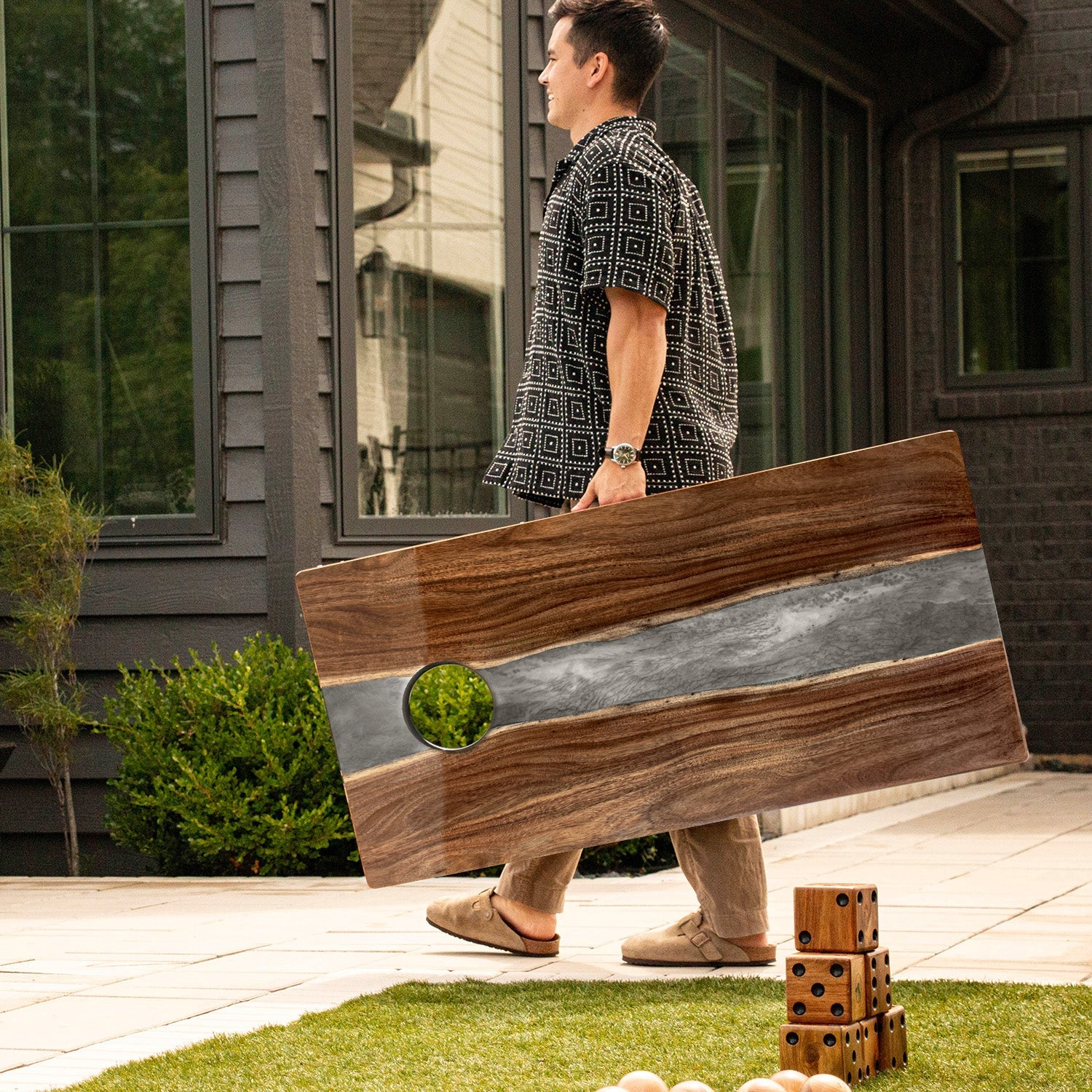 Person holding a large wooden board with a reflective surface outdoors.