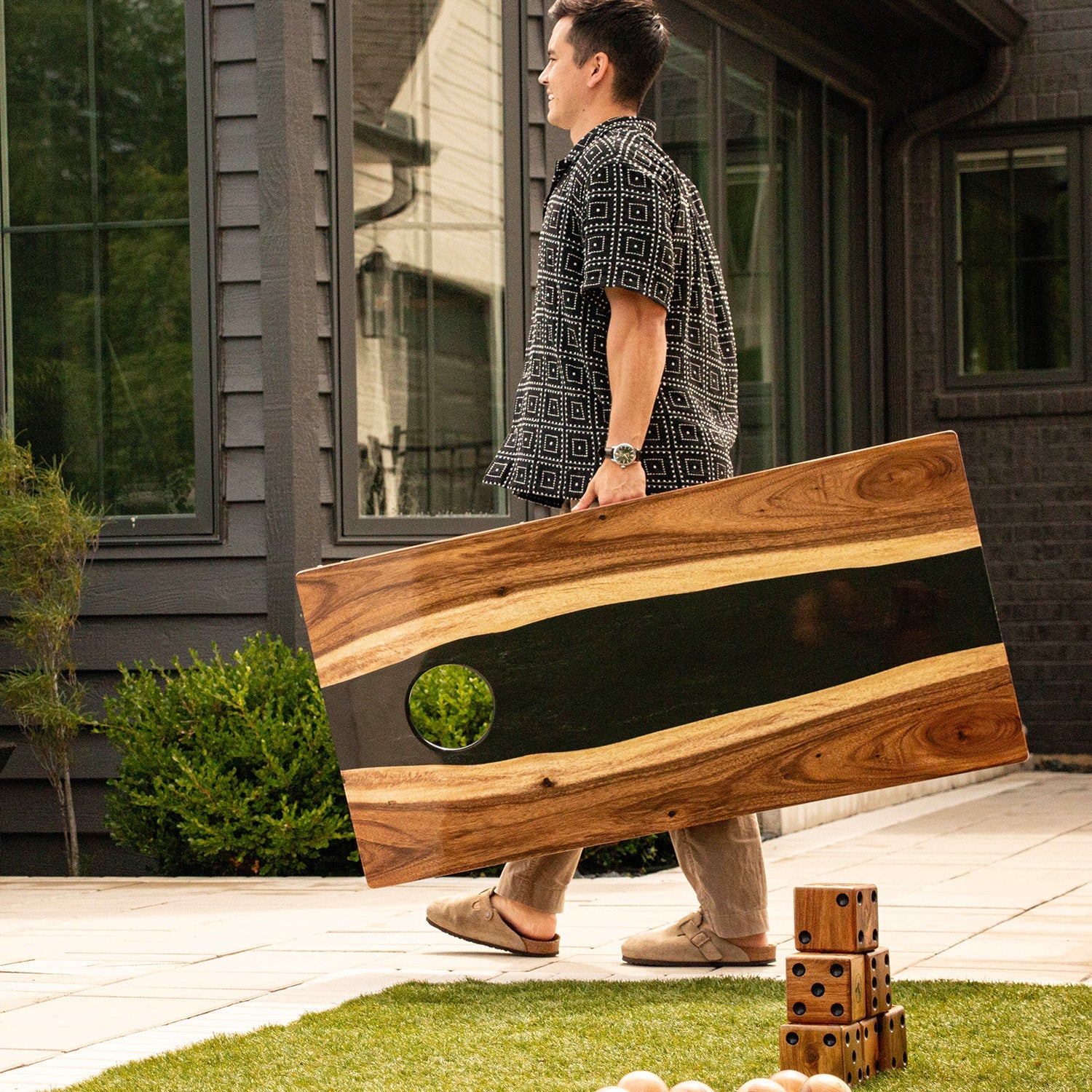 Person holding a large wooden board outdoors on a patio