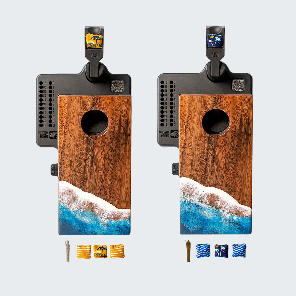 Two wooden cornhole boards with ocean design and accessories on a white background