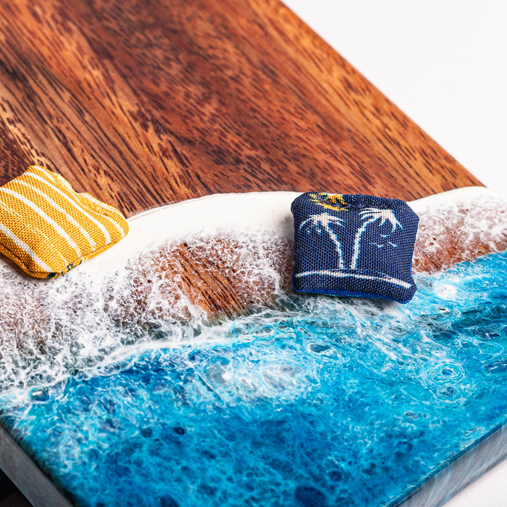 Wooden tray with blue resin design, white foam, and a yellow and blue striped towel.