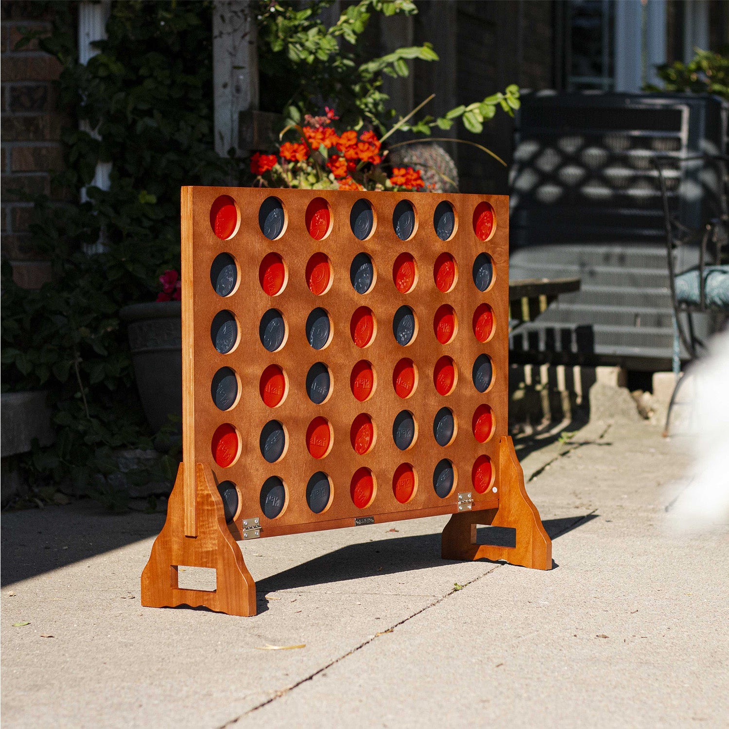 Outdoor game of Connect Four on a patio with plants and furniture in the background