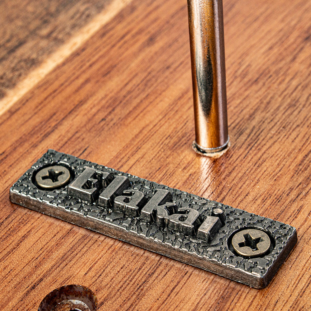 Metal nameplate with 'Elakaki' branding on a wooden surface