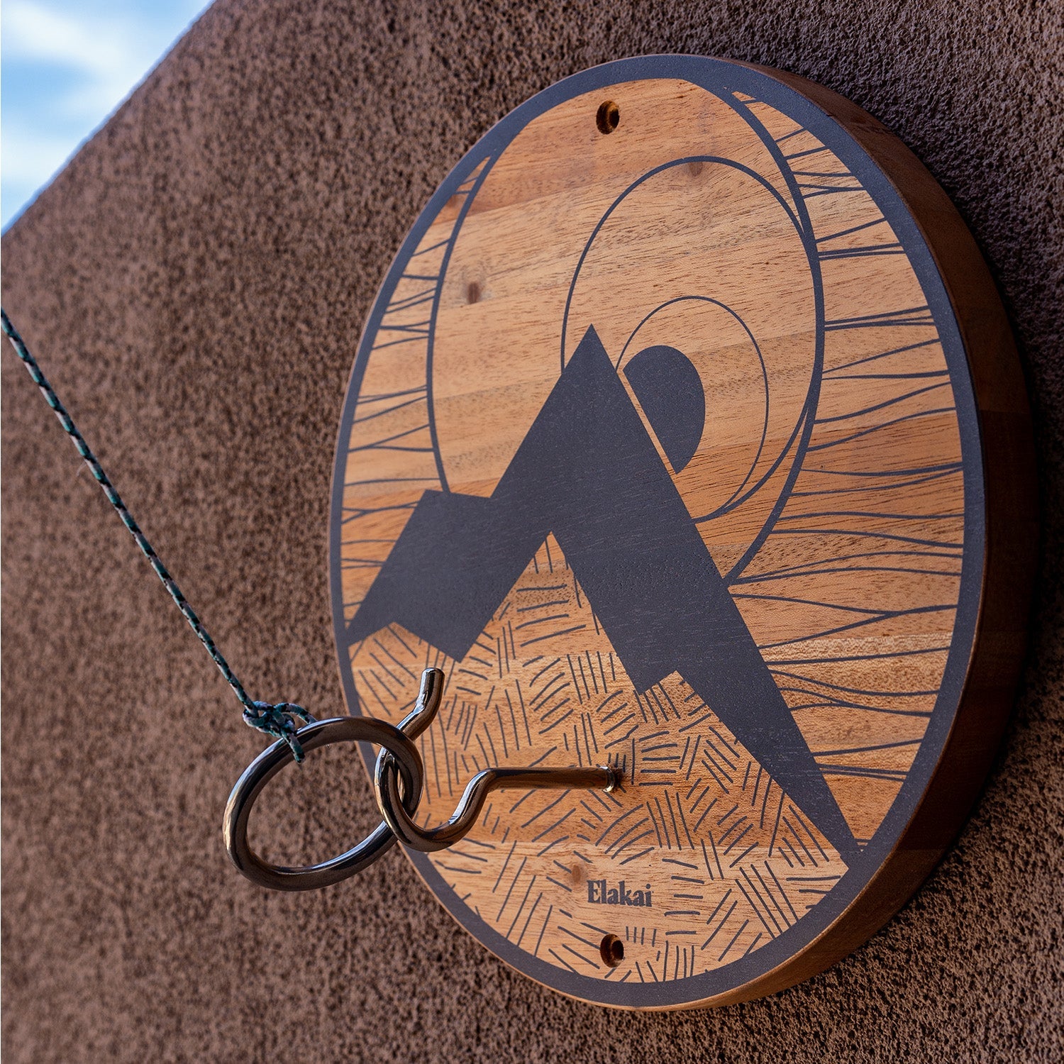 Wooden keychain with engraved design and 'Elakai' branding on a textured surface.