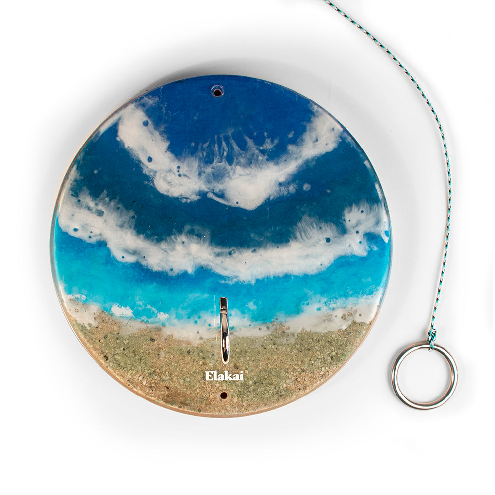 Round wall art piece with beach scene design on a white background