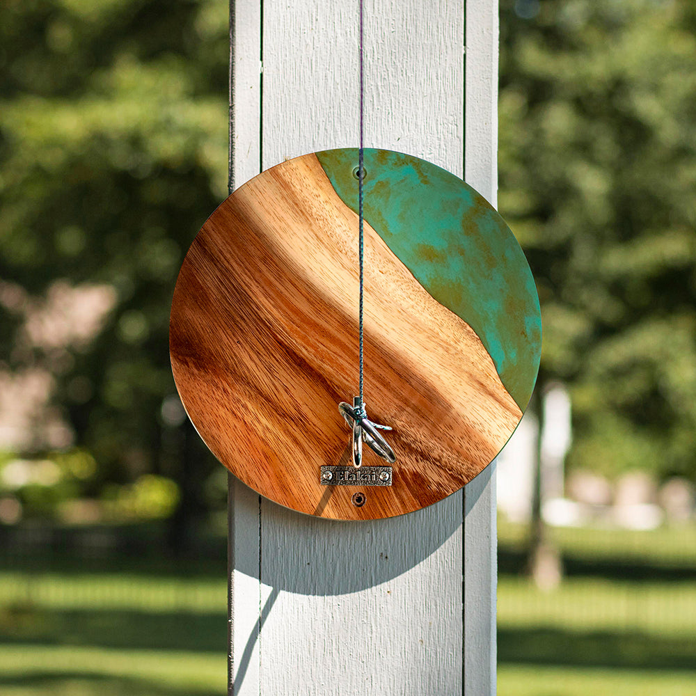 Wooden and metal circular object hanging on a wooden post with a blurred green background