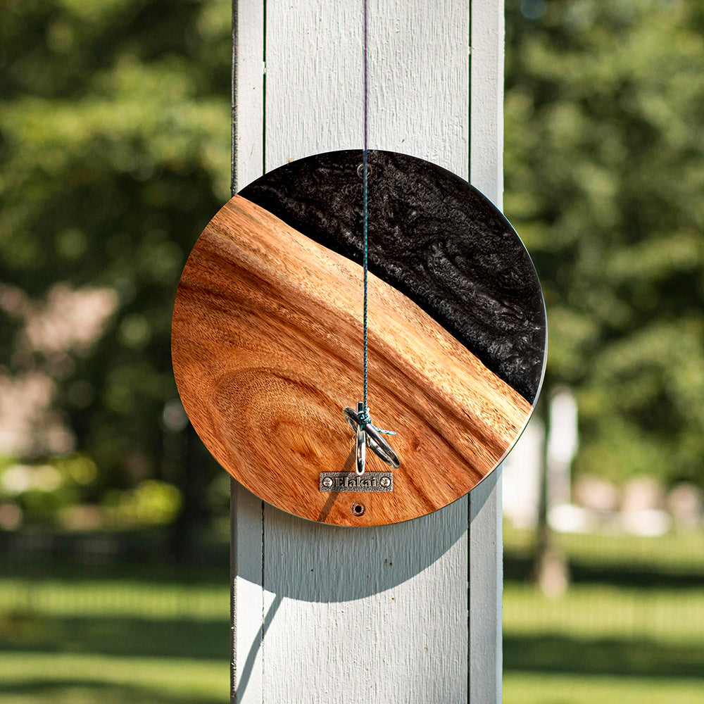 Wooden wind chime with natural finish on a blurred green outdoor background