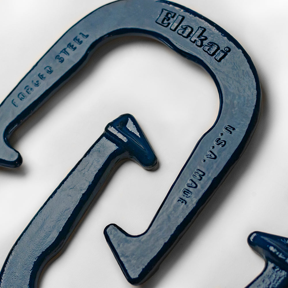 Close-up of a blue metal carabiner with 'Elakai' branding on a white background