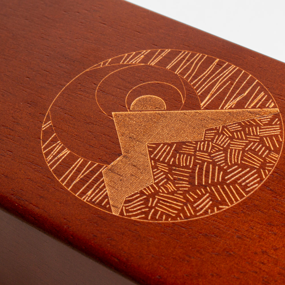 Wooden surface with a detailed geometric engraving of a letter 'G'.