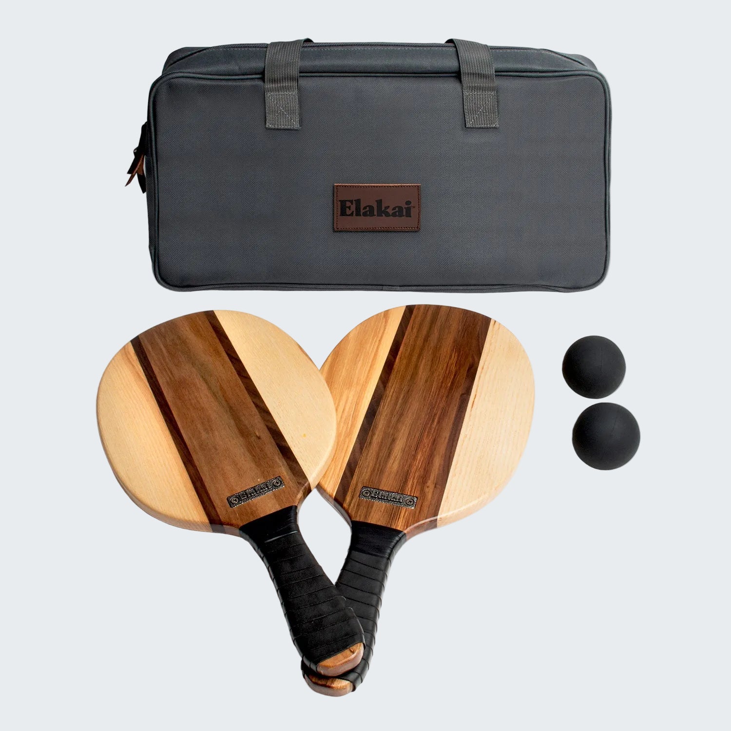 Two wooden pickleball paddles with black handles, two balls, and a gray carrying case on a white background. Elakat brand visible.