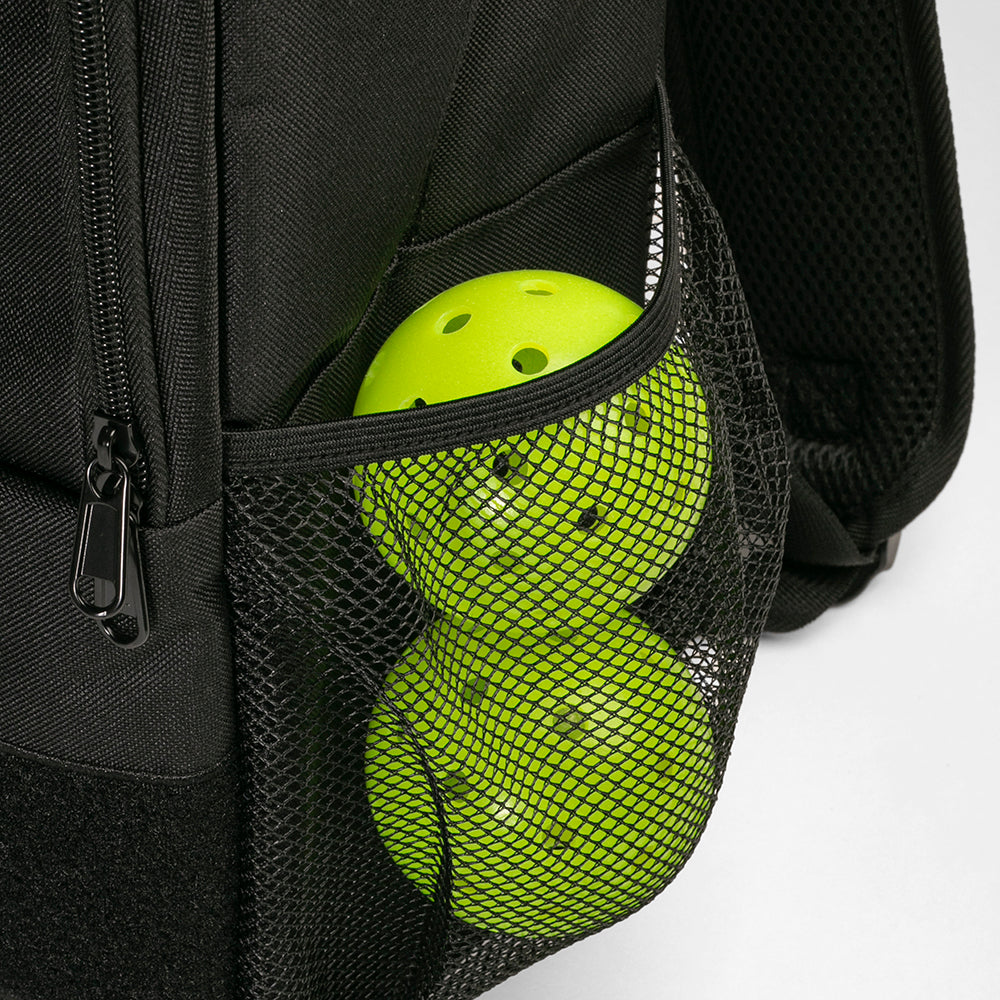 Black backpack with a mesh pocket containing a bright green pickleball ball on a white background