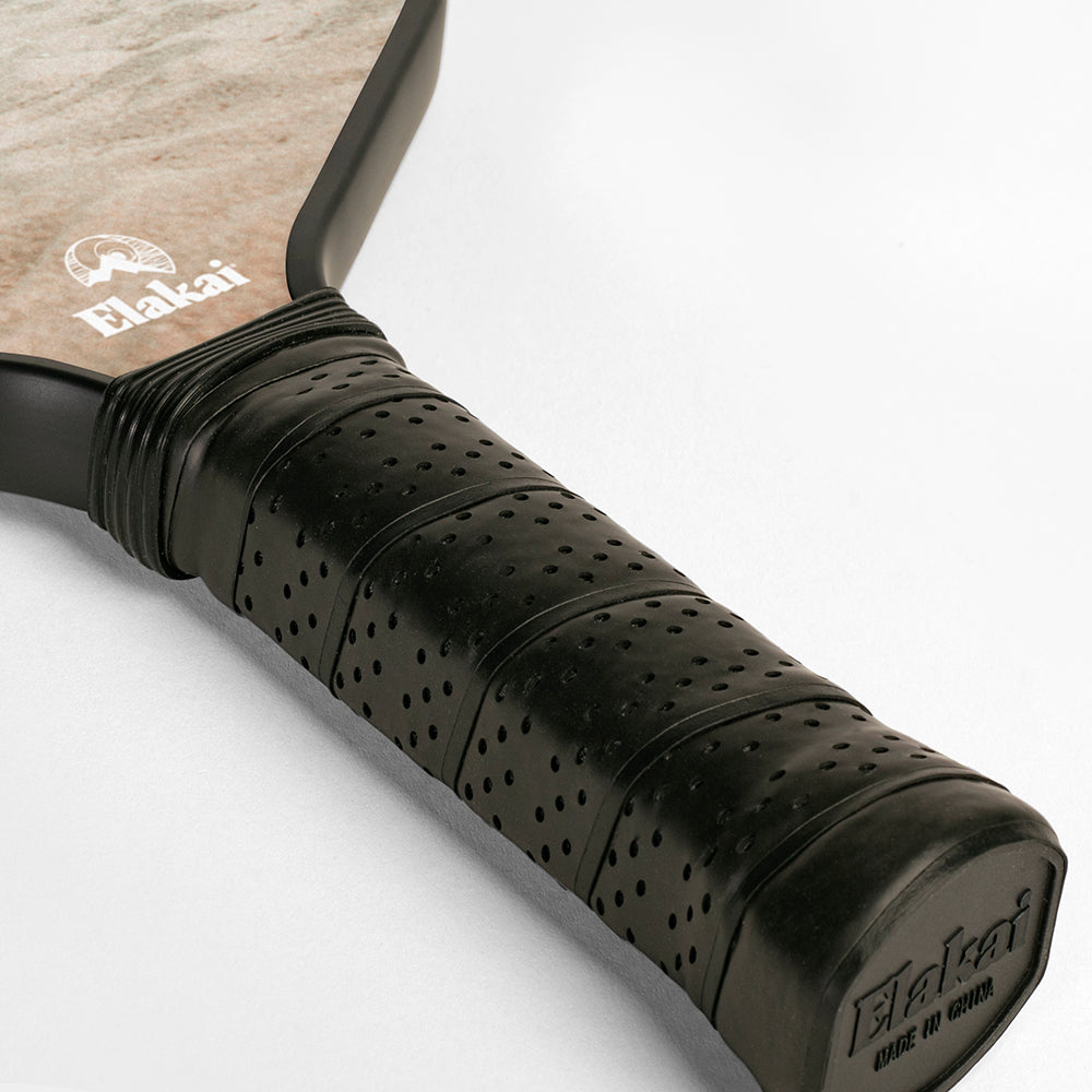 Close-up of a pickleball paddle with black grip and visible brand logo on a light gray background