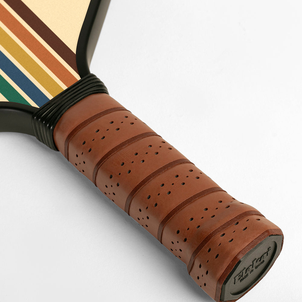 Close-up of a tennis racket handle with brown leather grip and colorful strings on a white background