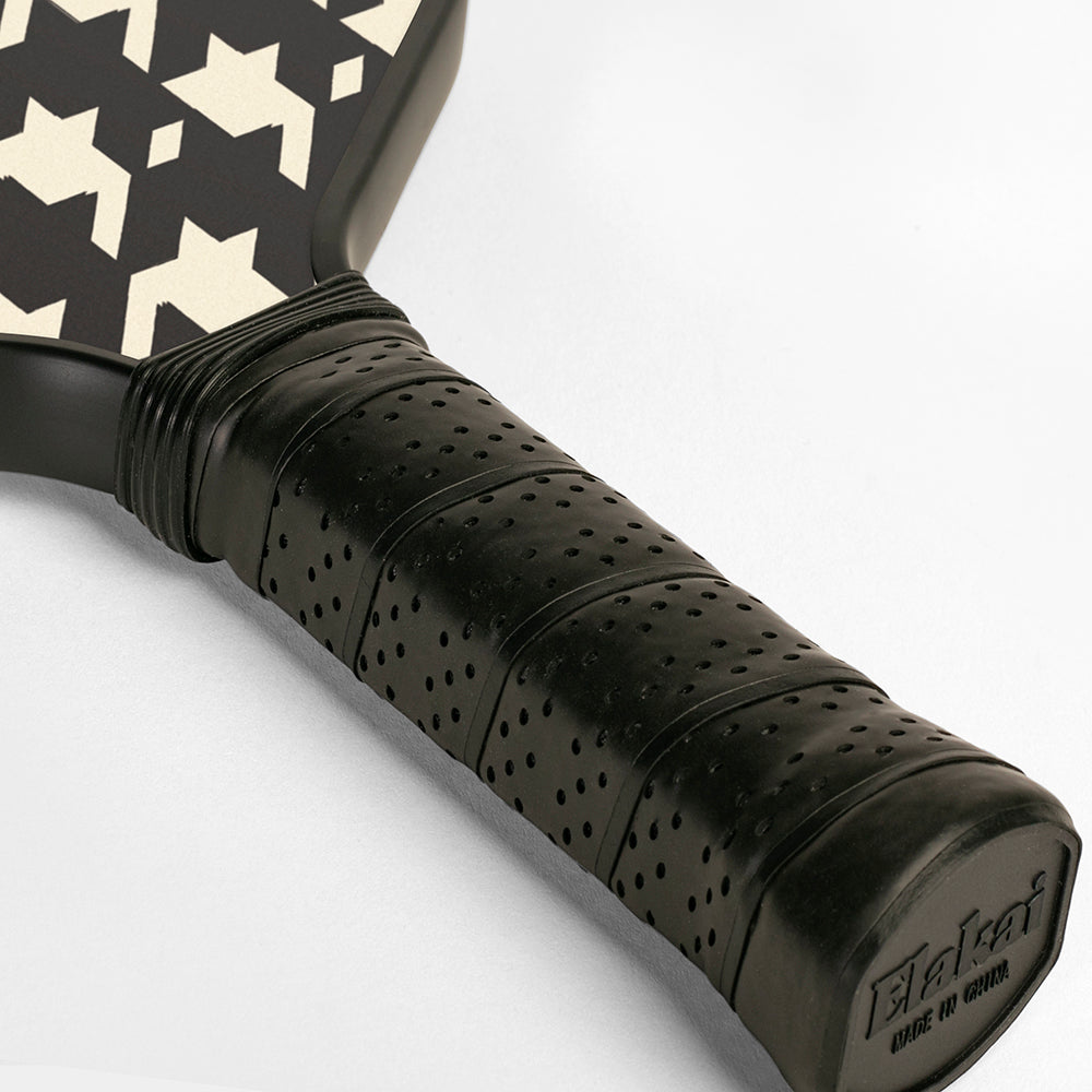 Close-up of a black pickleball paddle handle with patterned surface on a white background