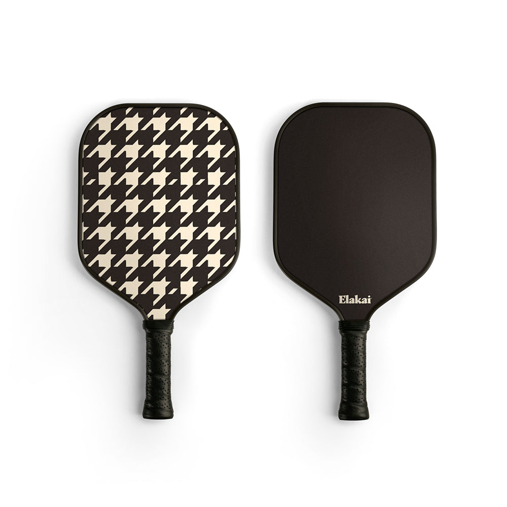 Two pickleball paddles, one with a houndstooth pattern and the other black, on a white background.