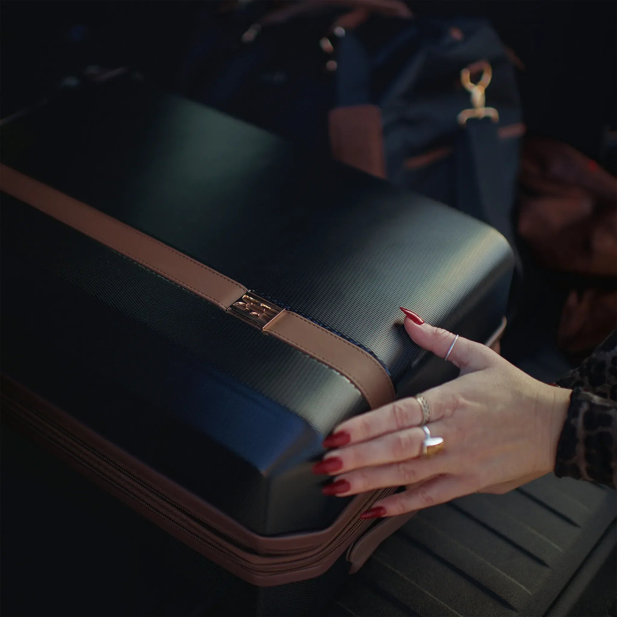 Person holding a suitcase with a focus on the handle and hand.