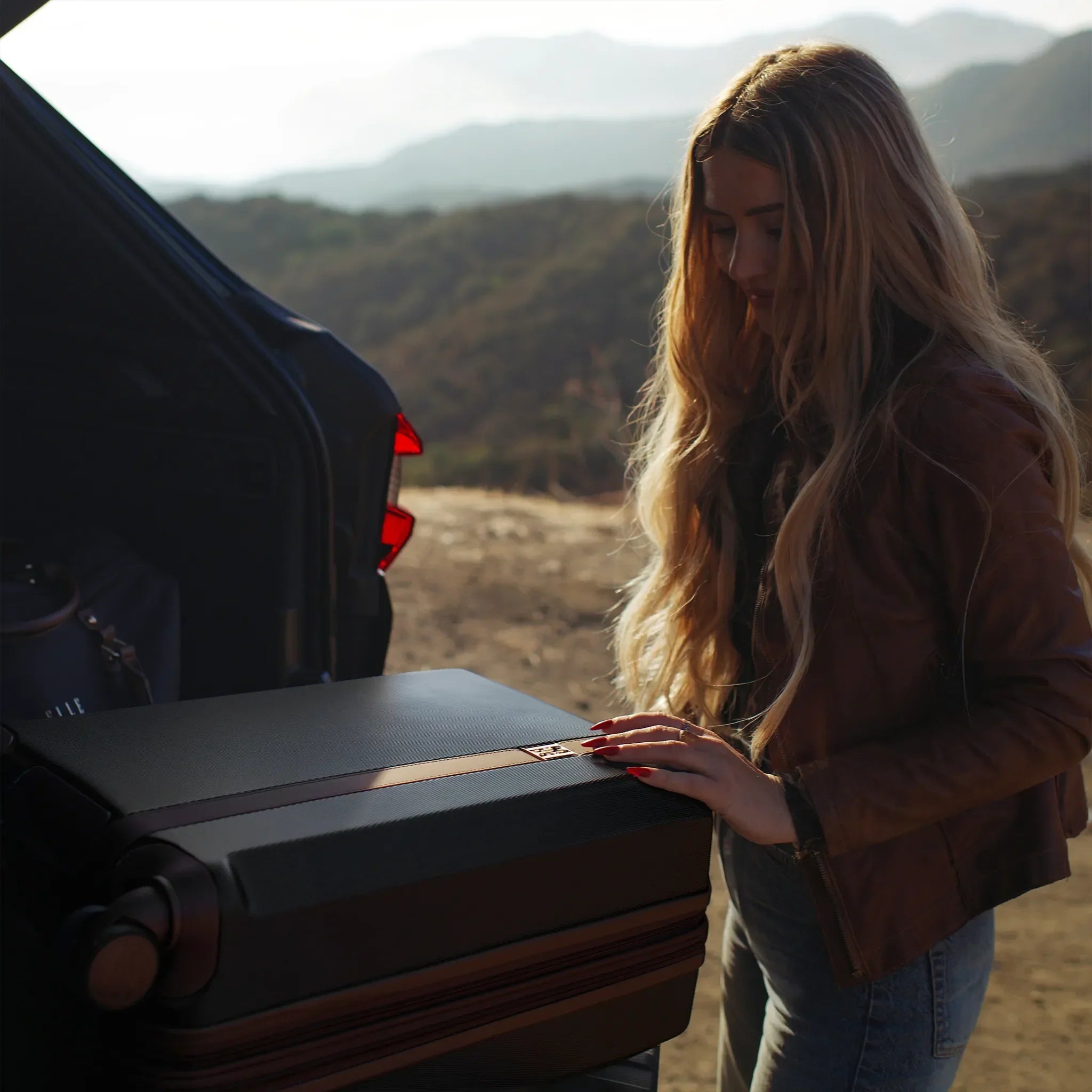 Woman standing next to an open car trunk in a desert landscape
