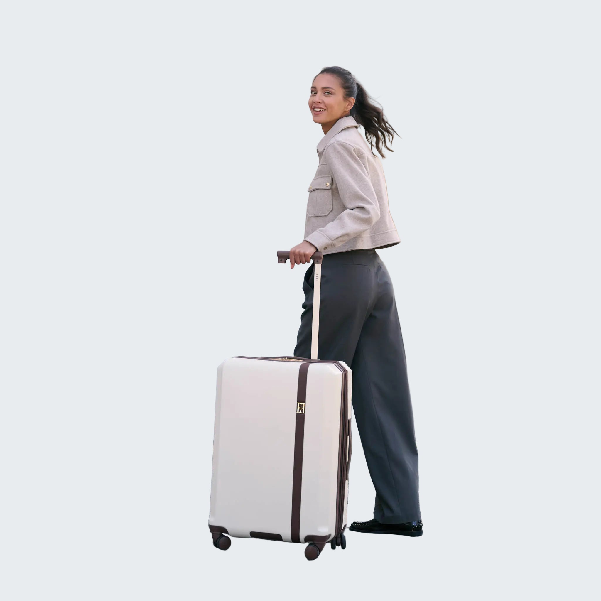 Woman pulling a white suitcase on a street in an urban setting