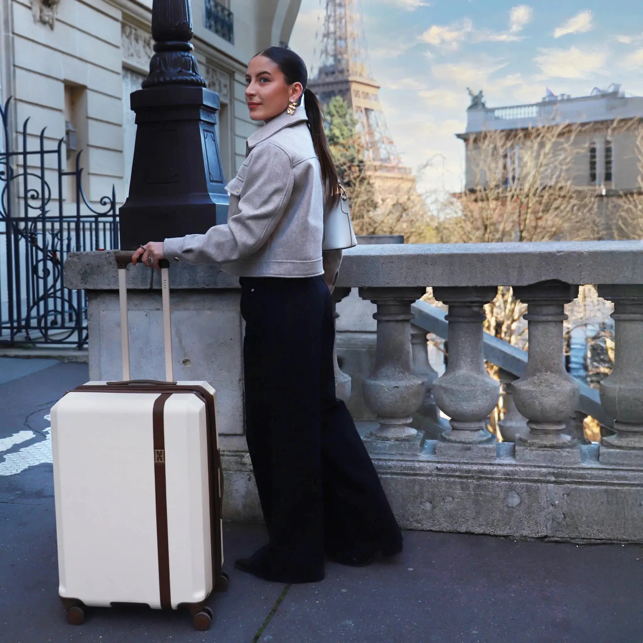 Woman with a suitcase standing in front of the Eiffel Tower