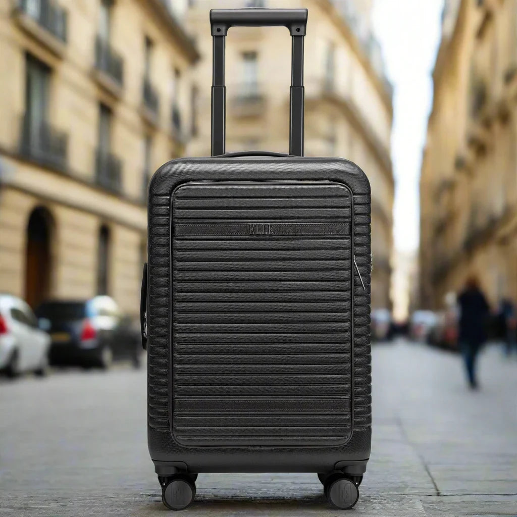 Black suitcase on wheels in the middle of a city street with blurred buildings and people in the background