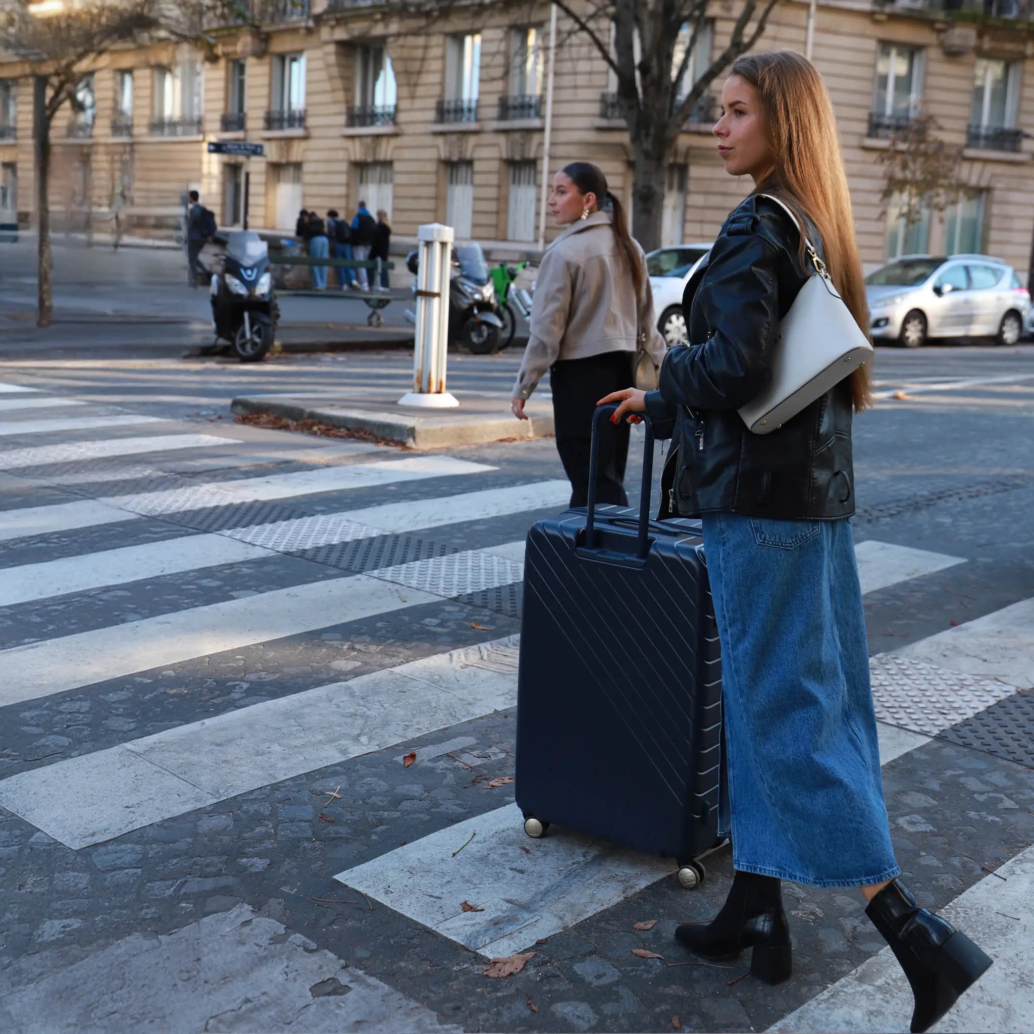 Woman with a suitcase crossing a zebra crossing in an urban setting