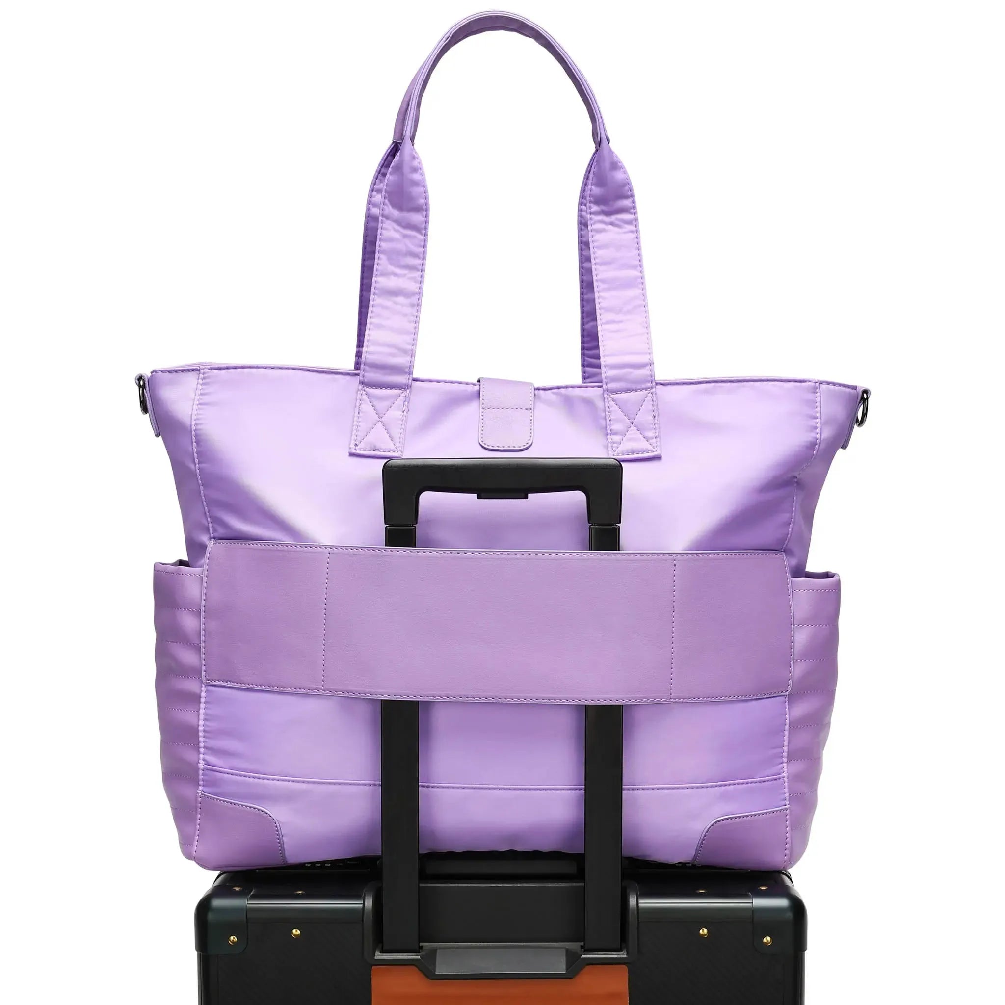 Purple tote bag with wheels stacked on top of a black suitcase on a white background