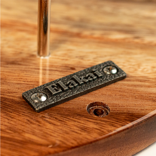 Metal plaque with 'Elakato' branding on a wooden surface