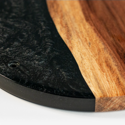 Close-up of a black and wooden cutting board on a white surface