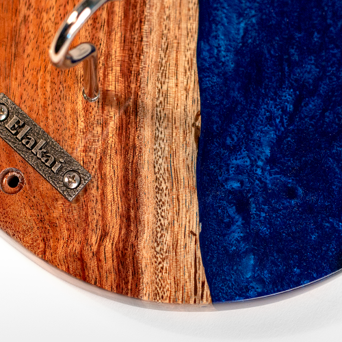Wooden and blue resin coaster with a metal tag on a white background