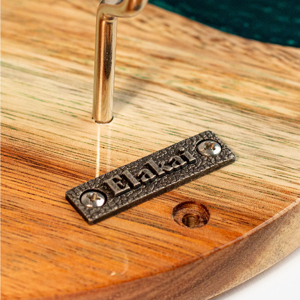 Wooden surface with a metal tag engraved with 'Elakat' being laser-etched.