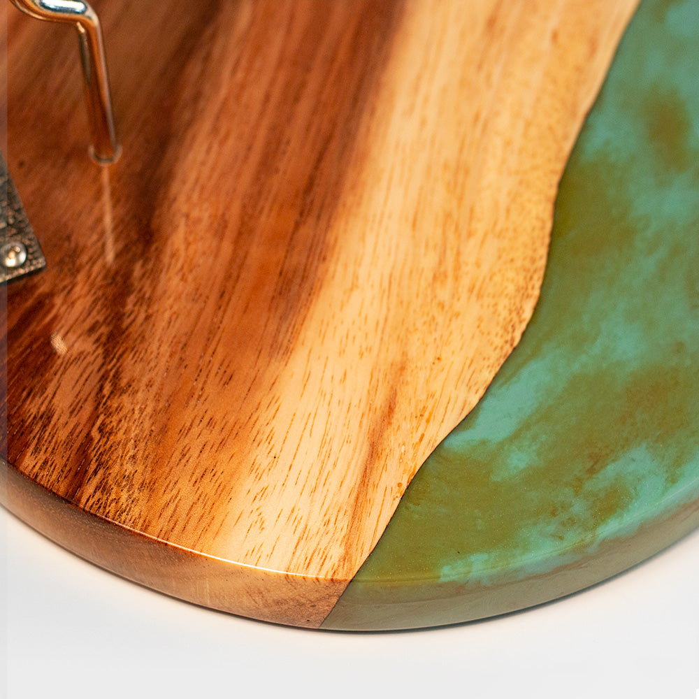 Wooden cutting board with a green resin edge on a white surface
