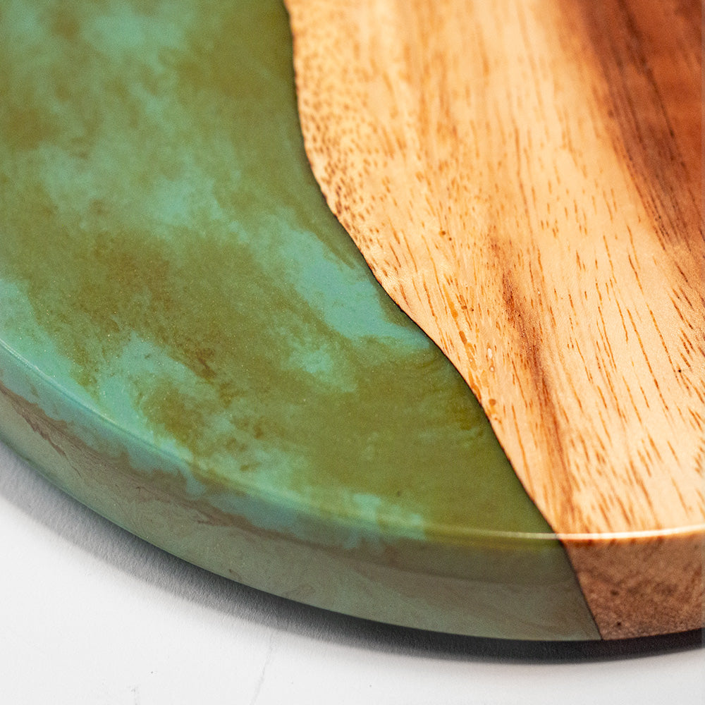 Close-up of a green resin and wood cutting board on a white surface