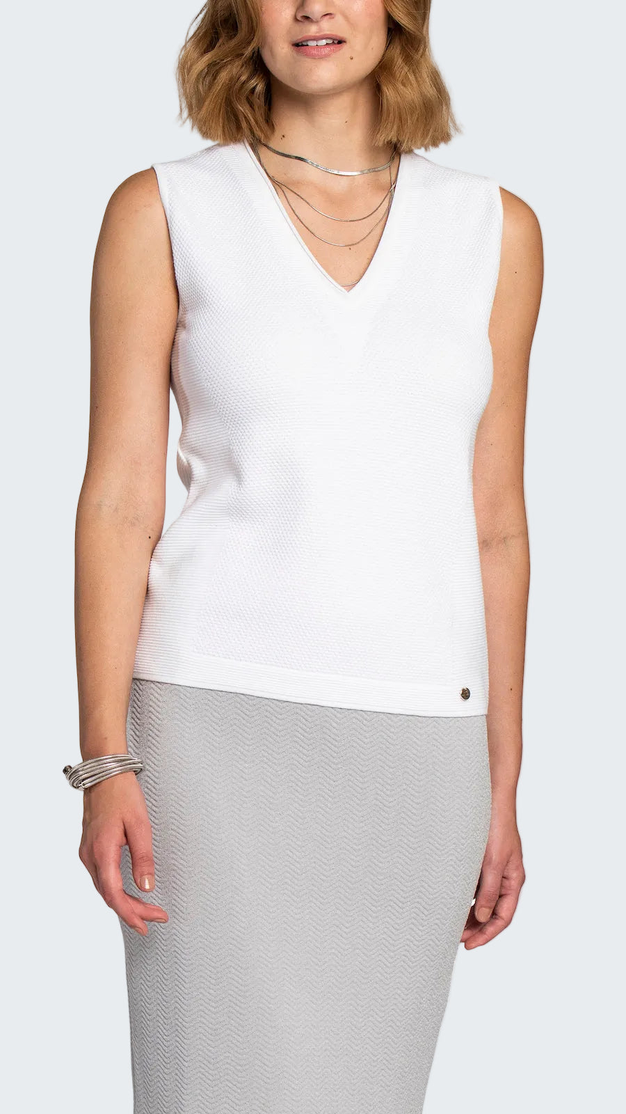 Woman wearing a white sleeveless top with a V-neckline on a white background