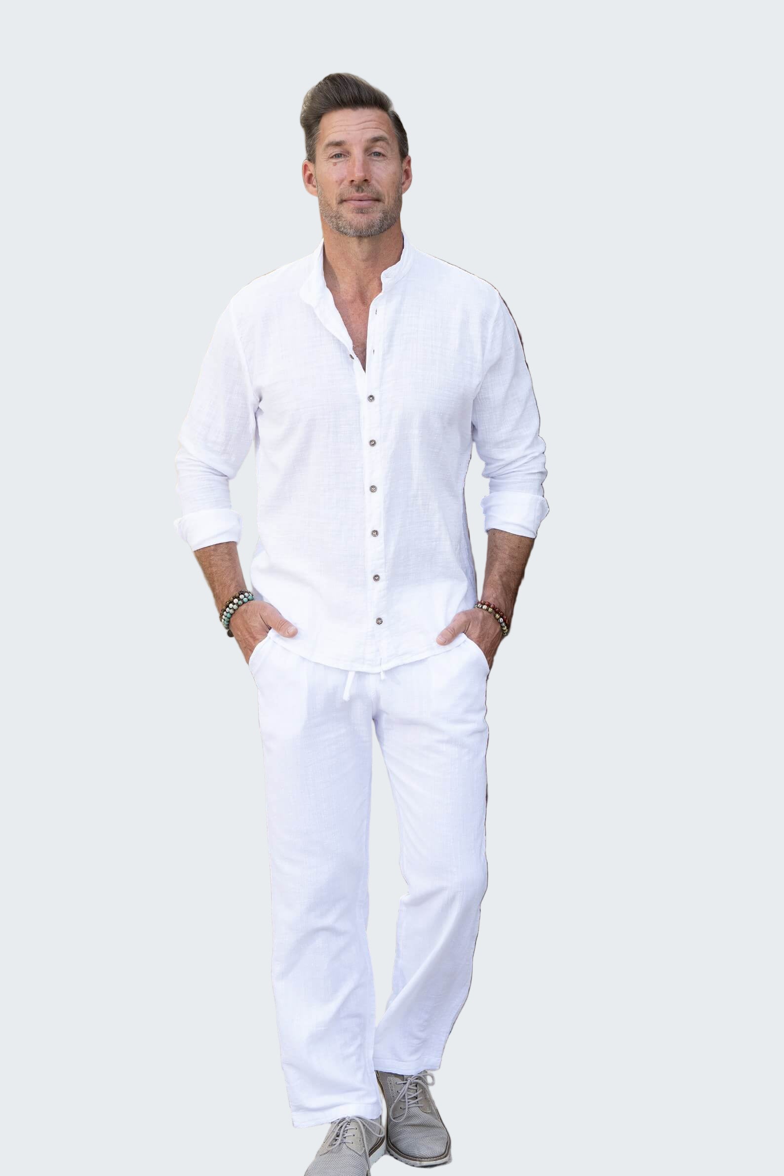 Man in a white outfit standing in front of a decorative wooden door.