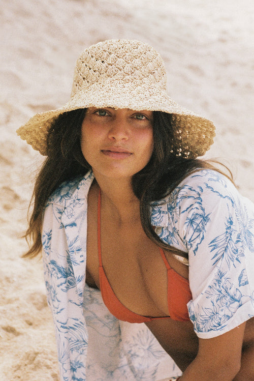 Woman wearing a straw hat and floral cover-up on a beach