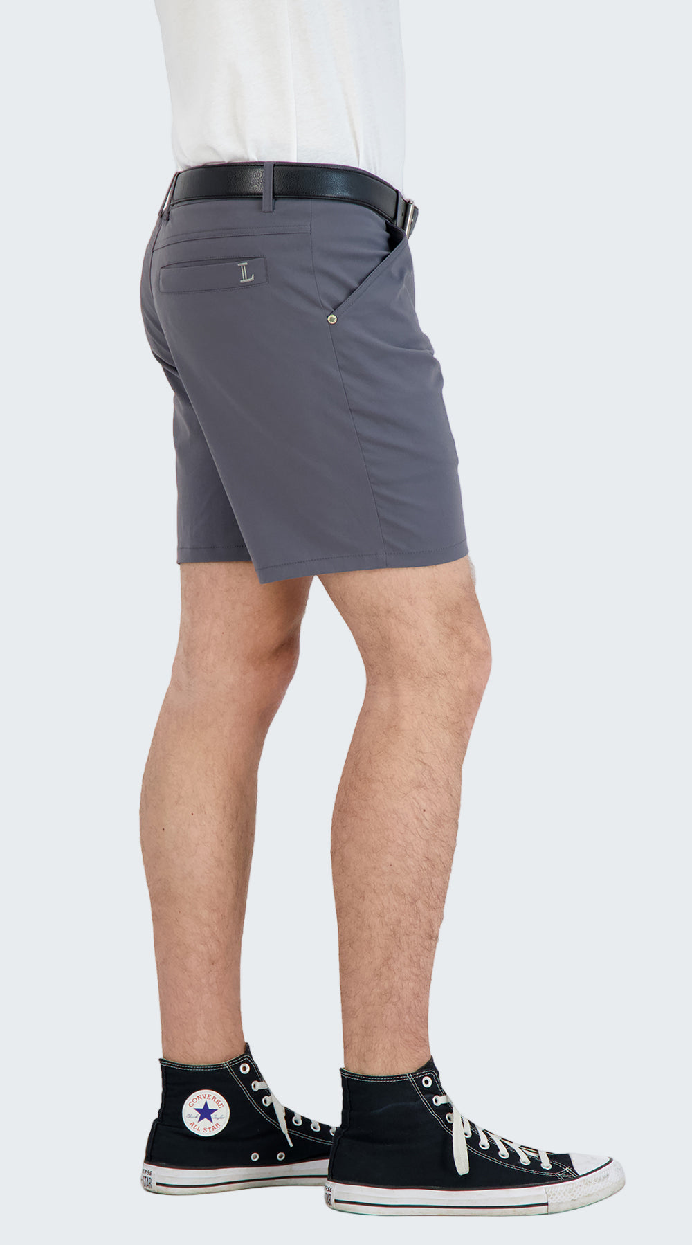 Person wearing gray shorts and black sneakers on a white background