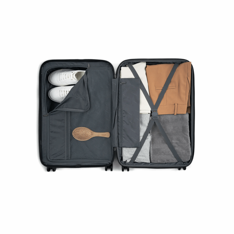 Open suitcase with clothes and a hairbrush on a white background