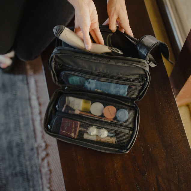 Open toiletry bag with travel-sized products on a wooden surface