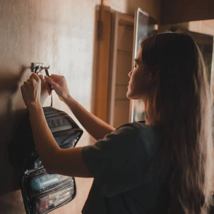Person installing a wall-mounted device in a room with wooden cabinets.