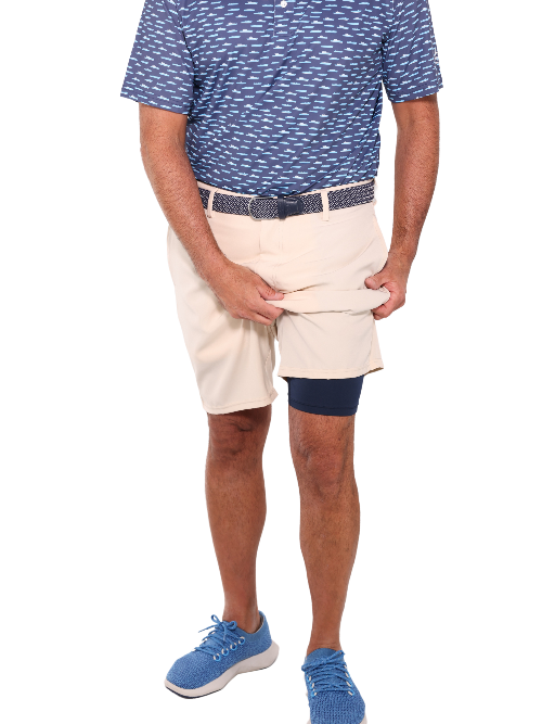 Person wearing a blue patterned polo shirt, beige shorts, and blue sneakers on a white background