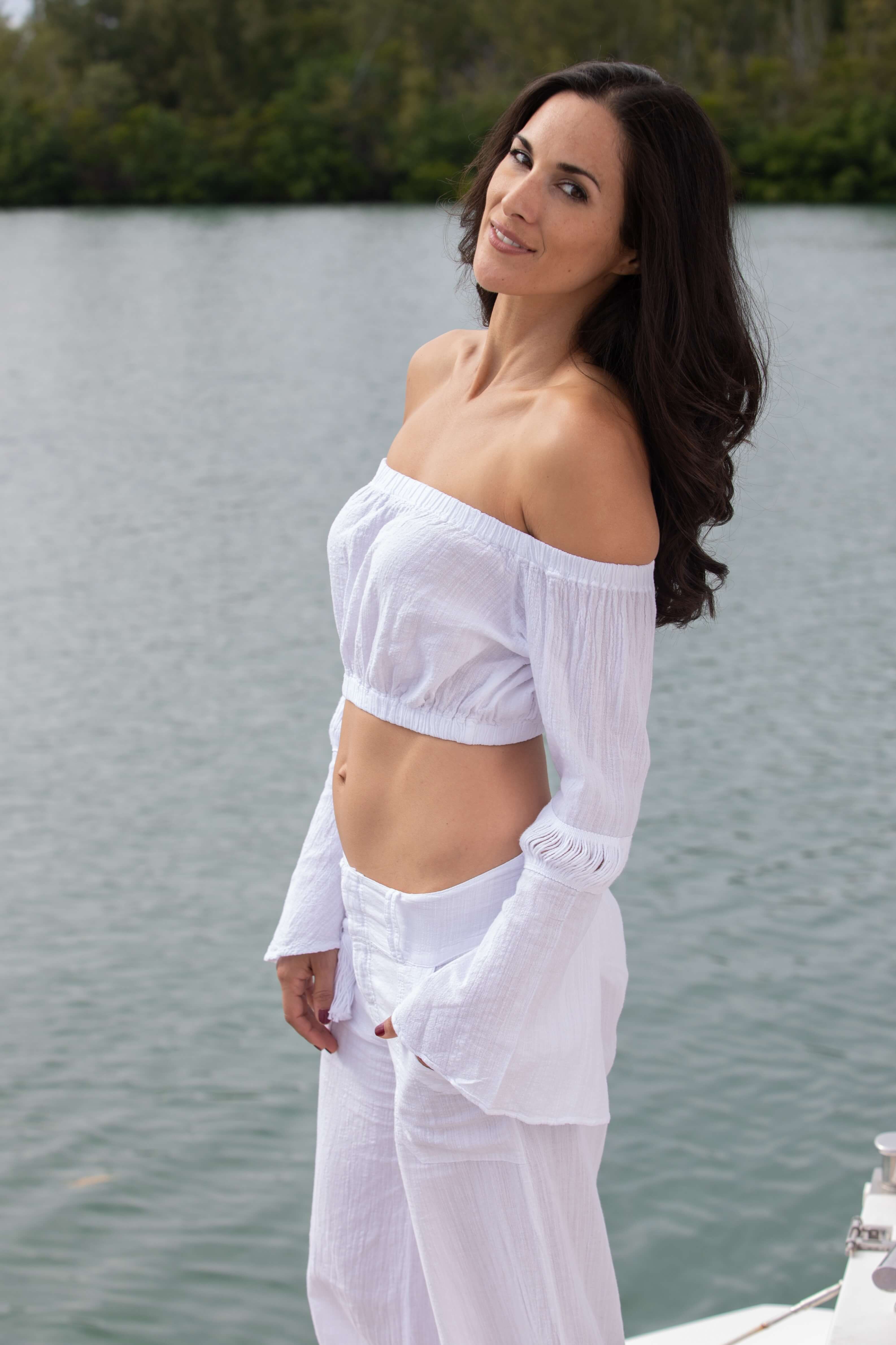 Woman in a white outfit standing by a body of water
