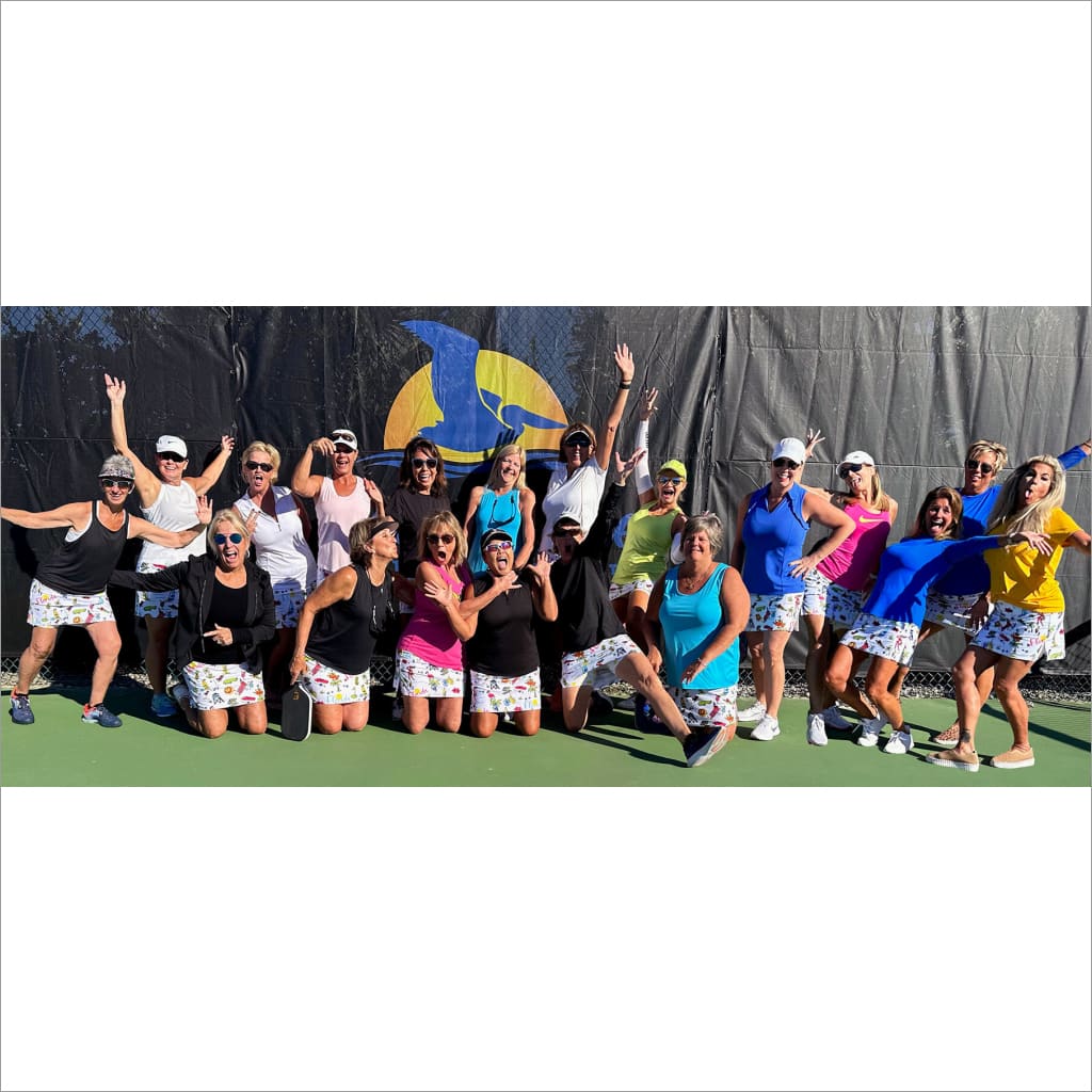 Group of people posing together on a tennis court with a colorful logo in the background.