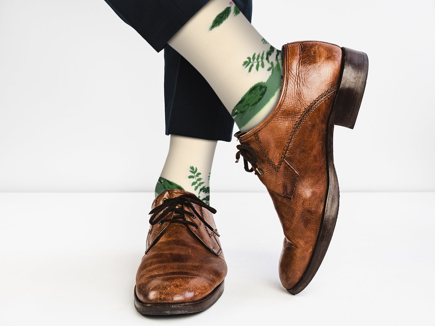 Brown leather shoes with white socks featuring green plant designs on a white background