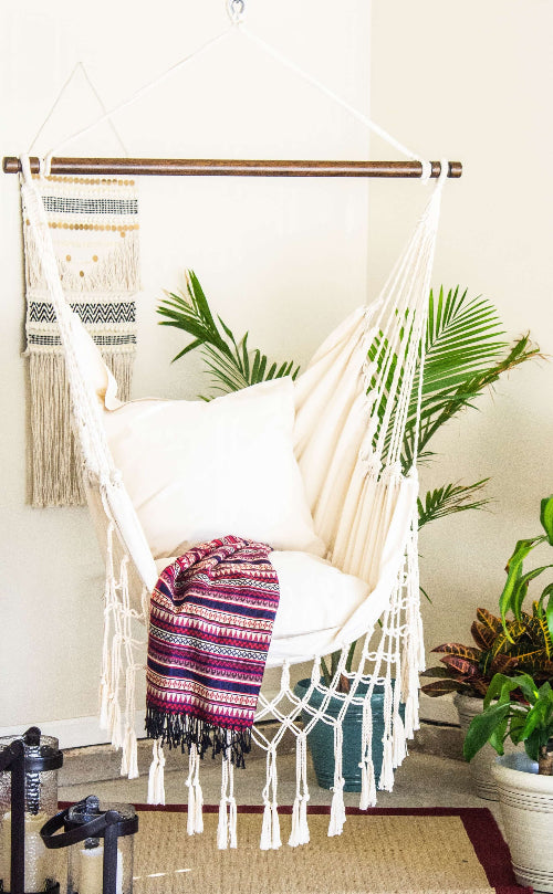 White hammock with colorful blanket in a room with plants