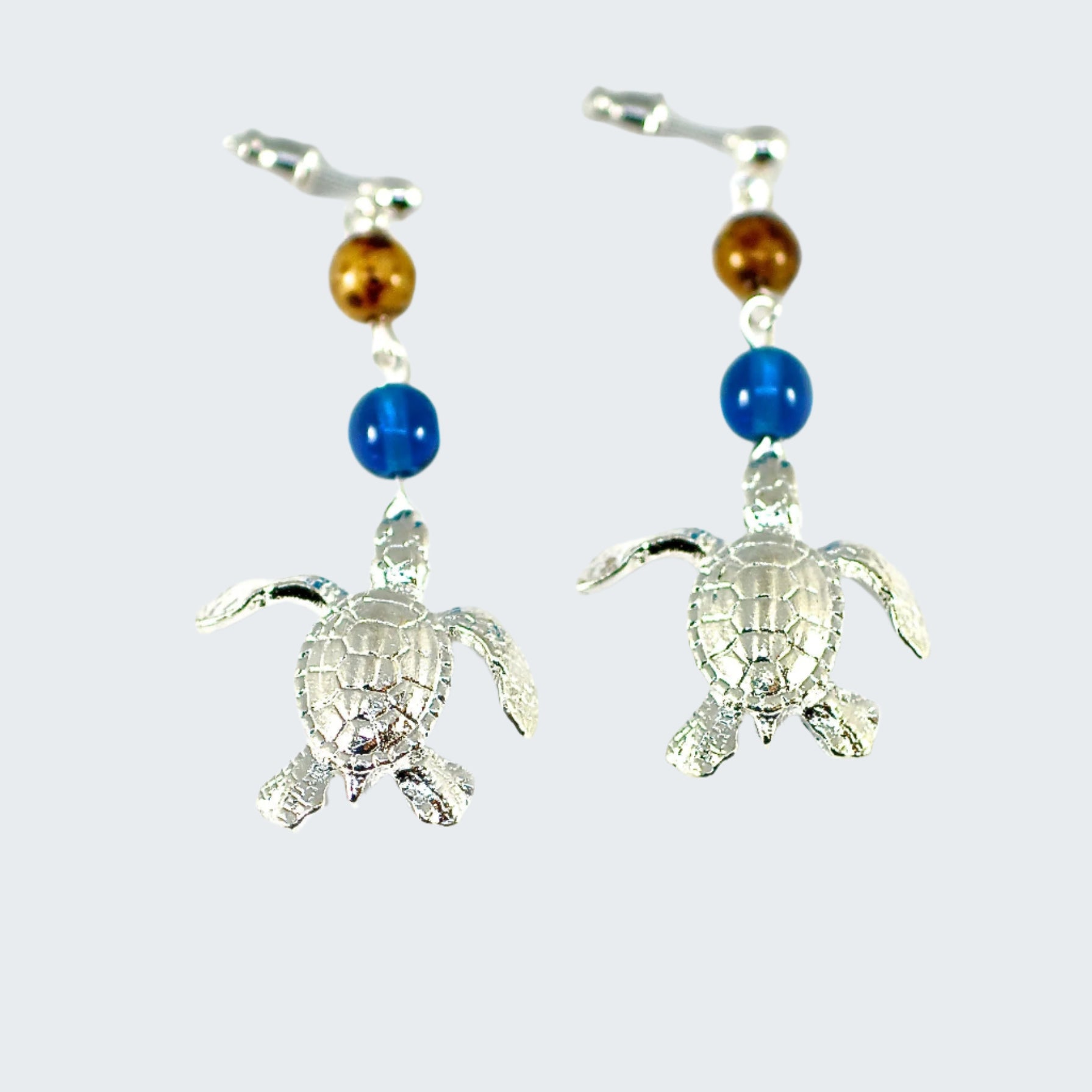Tortoise-shaped earrings with blue and brown beads on a white background