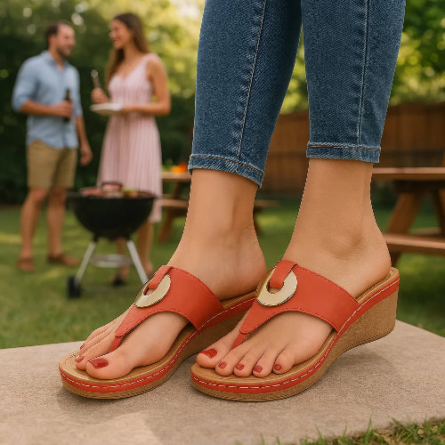 Red sandals with wooden soles worn by a person, with a blurred background of people at a barbecue.